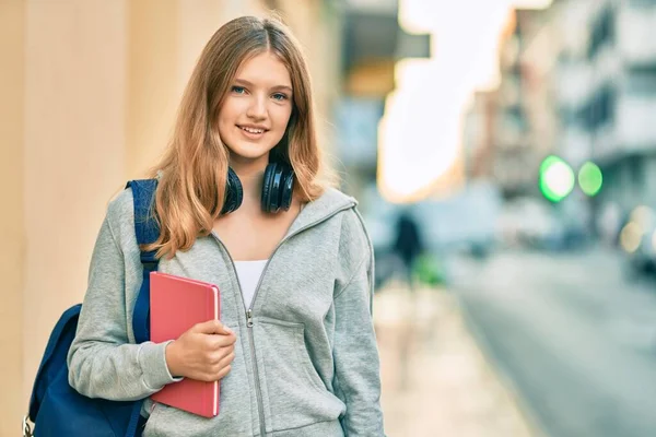 Hermosa Adolescente Estudiante Caucásica Usando Auriculares Sosteniendo Libro Ciudad —  Fotos de Stock