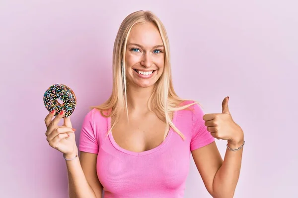 Jovem Loira Segurando Donut Sorrindo Feliz Positivo Polegar Para Cima — Fotografia de Stock