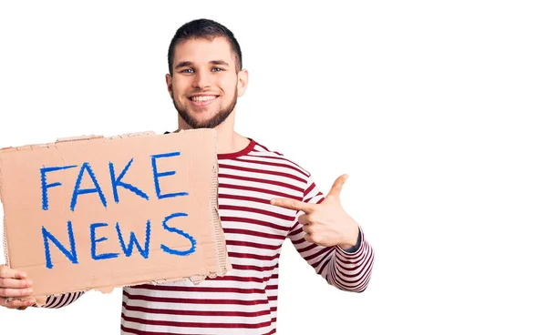 Joven Hombre Guapo Sosteniendo Banner Mensaje Noticias Falso Sonriendo Feliz — Foto de Stock