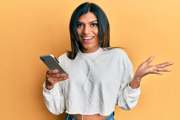 Młoda Latynoska Transseksualistka Używająca Smartfona Słuchawek Świętujących Osiągnięcie Szczęśliwym Uśmiechem — Zdjęcie stockowe