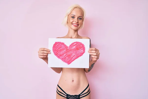 Молодая Блондинка Татуировкой Стоящая Рубашки Держа Сердце Рисует Улыбающуюся Счастливой — стоковое фото