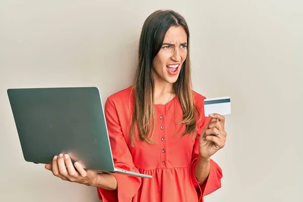 Młoda Piękna Kobieta Trzymająca Laptopa Kartę Kredytową Wściekła Wściekła Krzycząc — Zdjęcie stockowe