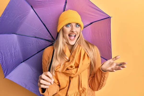 幸せな笑顔で達成を祝う紫色の傘を持っている若い白人女性と受賞式で手を上げ — ストック写真