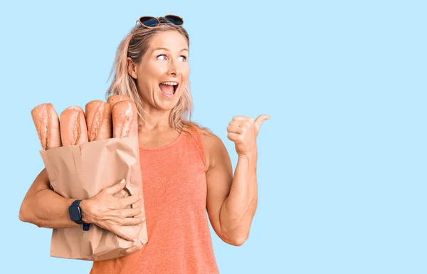 Middle Age Fit Blonde Woman Holding Paper Bag Bread Pointing — Stock Photo, Image