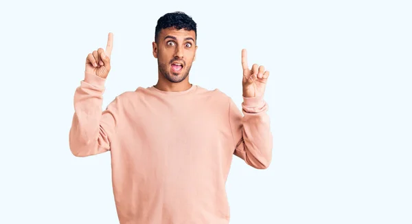 Young Hispanic Man Wearing Casual Clothes Smiling Amazed Surprised Pointing — Stock Photo, Image