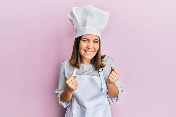 身穿职业厨师制服 头戴帽子的年轻漂亮女人兴奋地举起双臂 闭上双眼 微笑着庆祝胜利 获奖者概念 — 图库照片