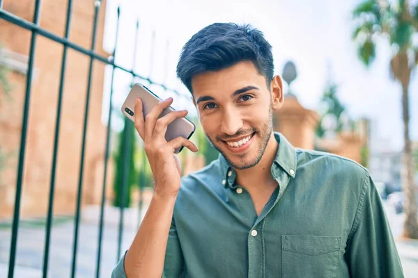 Joven Latino Sonriendo Feliz Escuchando Mensaje Audio Usando Teléfono Inteligente —  Fotos de Stock