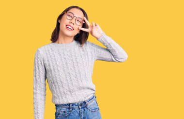 Genç, güzel Çinli kız günlük kıyafetler giyip barış sembolü yapıyor. Yüzünde parmaklarıyla gülümsüyor ve zafere gülümsüyor. 