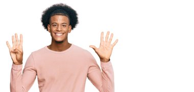 Afro saçlı Afrikalı bir adam günlük kıyafetlerini giyiyor ve dokuz numaralı parmaklarını gösterip gülümsüyor. Kendinden emin ve mutlu.. 