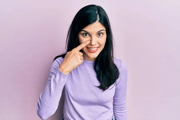 若いヒスパニック系の女性の顔や鼻に手指で指してカジュアルな服を着て 陽気な笑顔 美の概念 — ストック写真