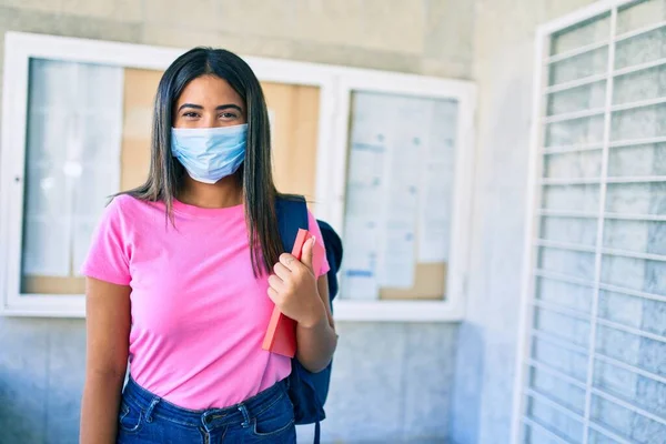 Νεαρή Λατίνα Φοιτήτρια Που Φοράει Ιατρική Μάσκα Και Κρατάει Βιβλίο — Φωτογραφία Αρχείου