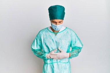 Genç, yakışıklı, cerrah üniforması giyen ve elleri karnında tıbbi maske takan bir adam. Çünkü hazımsızlık, acı verici bir hastalık ve kendini iyi hissetmiyor. Ağrı kavramı. 