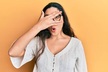 Güzel bir ortadoğulu kadın günlük kıyafetler ve gözlük takıyor. Şoka girip yüzünü ve gözlerini eliyle kapatıyor. Parmaklarından bakıyor. 