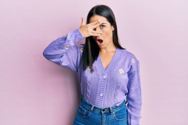 Genç esmer kadın, bahar hırkası ve çiçek desenli hırka giyiyor. Şoka girip yüzünü ve gözlerini eliyle kapatıyor. Parmaklarından bakıyor. 