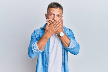 Sıradan kot ceket giyen yakışıklı kaslı adam yanlışlıkla elleri ile ağzını kapatırken şok oldu. gizli kavram. 
