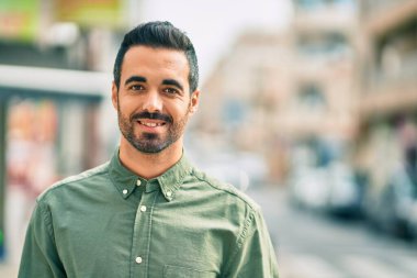 Genç İspanyol adam gülümseyerek şehirde mutlu mesut dikiliyor..