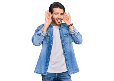 Gündelik giysiler giyen genç İspanyol adam iki elini de kulak hareketlerini duymaya çalışıyor. Dedikoduya meraklı. İşitme sorunu, sağır 