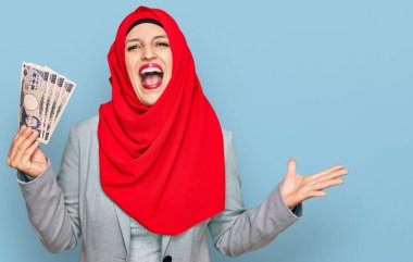 Güzel İspanyol kadın, elinde Japon Yen banknotları ile İslami tesettür takıyor zaferi mutlu bir gülümsemeyle kutluyor ve kazanan el kaldırıyor. 