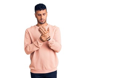Günlük kıyafetler giyen genç İspanyol adam ellerinde ve parmaklarında ağrı, eklem iltihabı 