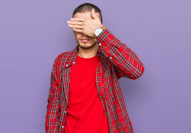 İspanyol asıllı genç adam, sıradan kıyafetler giyip, gözlerini eliyle kapatıyor, ciddi ve üzgün görünüyor. Görme, saklama ve reddetme konsepti 
