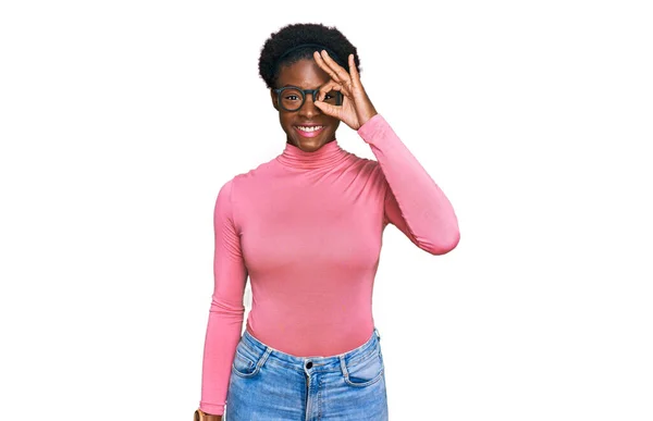 若いですアフリカ系アメリカ人の女の子身に着けていますカジュアル服や眼鏡をかけますOkジェスチャーとともに手笑顔 目を通して指で幸せな顔 — ストック写真