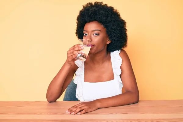 年轻的非洲裔美国女人 一头黑发 坐在家里桌上喝着一杯清水 — 图库照片