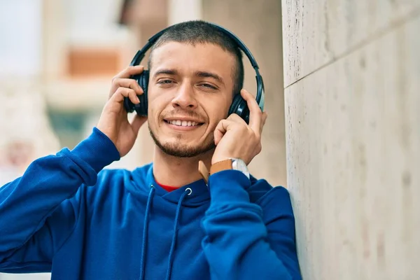 若いですヒスパニック男笑顔幸せな使用ヘッドフォンで市内 — ストック写真