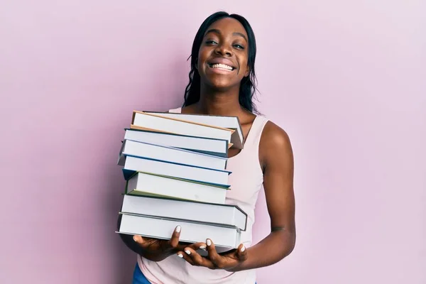 Joven Mujer Afroamericana Sosteniendo Libros Sonriendo Con Una Sonrisa Alegre —  Fotos de Stock