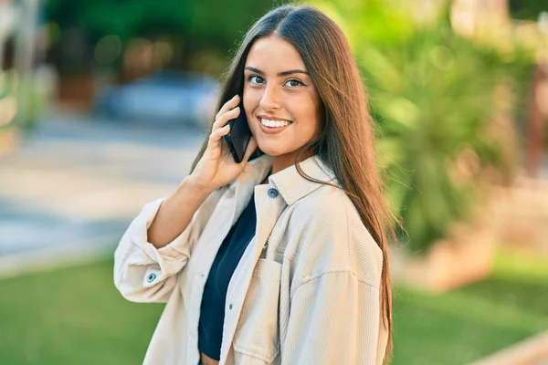 若いですヒスパニック系の女の子笑顔幸せな話上のスマートフォンで公園 — ストック写真