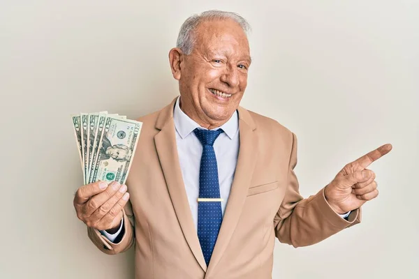 Starszy Kaukaski Mężczyzna Trzymając Dolary Uśmiechając Szczęśliwy Wskazując Ręka Palec — Zdjęcie stockowe