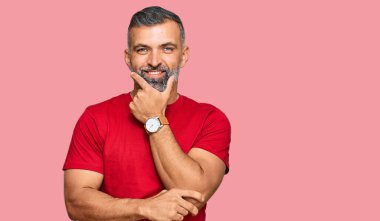 Orta yaşlı, sıradan kıyafetler giyen, kameraya kendinden emin, kolları çapraz ve çenesi havada gülümseyen yakışıklı bir adam. Olumlu düşünmek. 