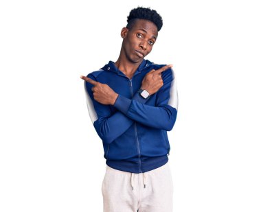 Spor giyimli genç Afro-Amerikan adam her iki tarafı da parmaklarıyla işaret ediyor, farklı yönlere. 