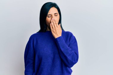 Gündelik giysiler giyen genç beyaz kadın ağzıyla ağzını kapatmaktan sıkılmış. Huzursuz ve uykulu.. 