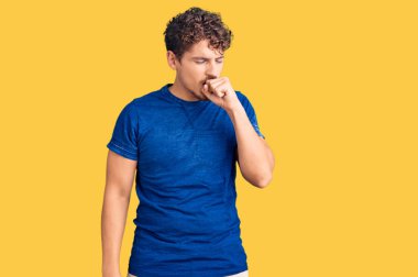 Kıvırcık saçlı, günlük kıyafetler giyen, kendini iyi hissetmeyen ve soğuk algınlığı veya bronşitin belirtisi olarak öksüren genç yakışıklı bir adam. sağlık hizmeti kavramı. 