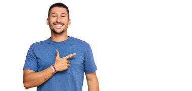 Yüzünde mutlu ve doğal bir ifade olan, elleri ve parmaklarıyla yüzünü gösteren, güler yüzlü, sıradan kıyafetler giyen yakışıklı bir adam. 