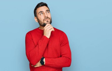 Elleri çenesinde gündelik giysiler içinde soru soran genç İspanyol bir adam, düşünceli bir ifade. Gülümseyen ve düşünceli bir yüz. şüphe kavramı. 