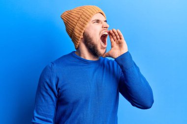 Gündelik kazak ve yün şapka giyen genç yakışıklı adam el ele tutuşarak bağırıyor ve çığlık atıyordu. iletişim konsepti. 