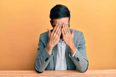 Ofiste çalışan genç İspanyol bir adam. Ağlarken yüzünü ellerle kapatan üzgün bir ifadeyle. depresyon kavramı. 