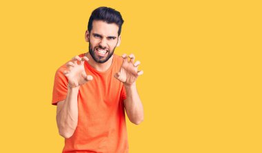 Sakallı, sıradan tişörtlü, komik gülümseyen, kedi gibi pençeli, agresif ve seksi bir ifade sergileyen genç yakışıklı bir adam. 