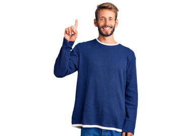 Yakışıklı, sakallı, sıradan bir süveter giyen, bir numaralı parmağını gösterip gülümseyen, kendinden emin ve mutlu bir adam.. 