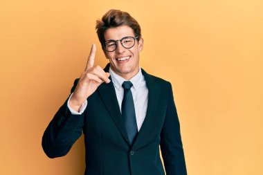 Takım elbiseli ve kravatlı yakışıklı beyaz adam başarılı bir fikirle işaret ediyor. Heyecanlı ve mutlu. Bir numara.. 