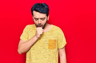 Günlük kıyafetler giyen genç İspanyol adam kendini iyi hissetmiyor ve soğuk algınlığı veya bronşitin belirtisi olarak öksürüyor. sağlık hizmeti kavramı. 