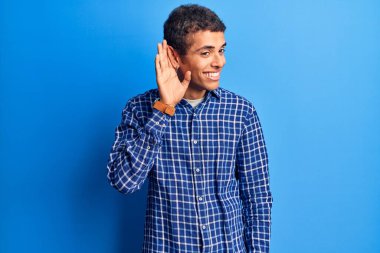 Genç Afro-Amerikan bir adam, günlük giysiler giymiş, ağzı kulaklarına varan bir gülümsemeyle dedikodu ve dedikoduları dinliyor. Sağırlık kavramı. 