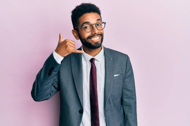 Sakallı, takım elbiseli ve kravatlı yakışıklı İspanyol bir iş adamı telefonla el ve parmaklarıyla telefonla konuşur gibi gülümsüyor. iletişim kavramları. 