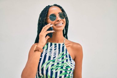 Genç Afrikalı Amerikalı kadın gülümsüyor. Şehirdeki akıllı telefondan mutlu bir şekilde konuşuyor..