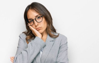 İş kıyafetleri giyen genç esmer kadın kollarını kavuşturarak depresyondan yorgun ve sıkılmış göründüğünü düşünüyor.. 