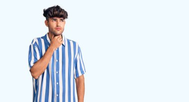 Günlük giysiler giyen genç İspanyol adam ağrılı boyuna dokunuyor, grip, mantar ve enfeksiyon yüzünden boğaz ağrısı çekiyor. 