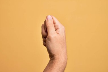 İzole edilmiş sarı arka planda parmaklarını gösteren beyaz bir adamın eli. Parmak, iş ve reklamla boş bir alan tutuyor.