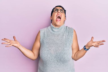 Artı, sıradan kıyafetler giyen, gözlüklü, deli gibi bağıran ve bağıran esmer bir kadın. Agresif bir ifade ve kollar havada. hüsran kavramı. 