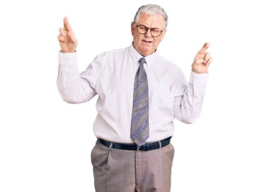 İş kıyafetleri giyen yaşlı gri saçlı adam umut ve gözlerle gülümseyerek el işareti yapıyor. Şans ve batıl inançlar. 